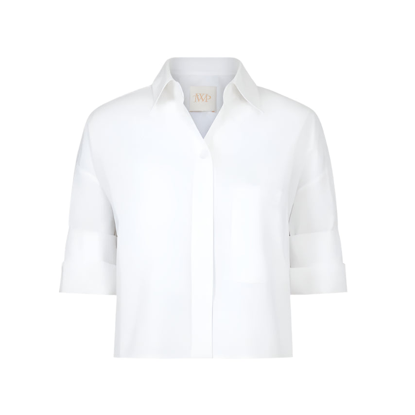 The TWP Next Ex Shirt is a white, short-sleeved, collared button-up with a chest pocket and boxy silhouette, shown against a plain background.