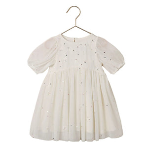 The Noralee Girls’ Luna Dress is a white babydoll mini dress for children, featuring short puff sleeves and multicolored sequins, shown on a gold hanger against a white background.