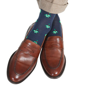 A person wearing brown leather loafers and Dapper Classics Dress Navy with Green and White Mistletoe Fine Merino Wool Mid-Calf Socks, paired with light brown trousers.