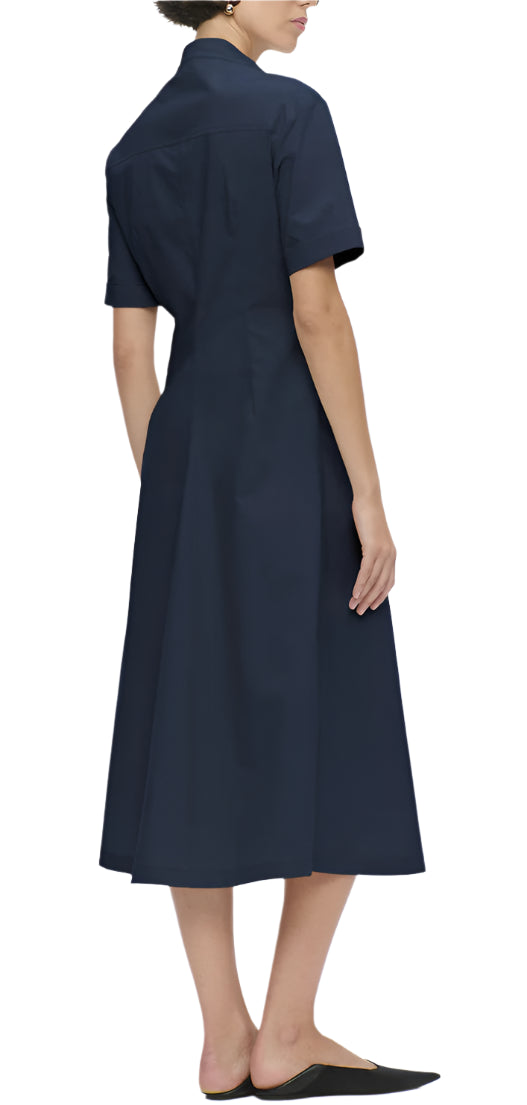 A person is shown from the back wearing the Callas Milano Noor Dress, a navy blue, short-sleeved, collared shirt dress with a flattering fit, paired with black flat shoes.