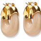 The Organic Gold Hoops by Lizzie Fortunato are beige resin chunky hoop earrings featuring shiny gold-tone hardware at the top.