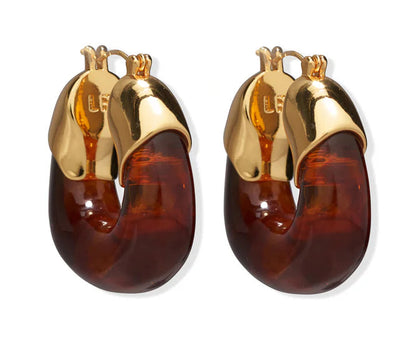 The Lizzie Fortunato Organic Gold Hoops feature gold-toned metal tops and dark amber resin bottoms, shown against a white background.