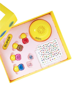 The Super Smalls Self Care Nail Kit includes a yellow buzzer, four colorful stampers, two dice, and sticker sheets in a yellow box with a pink tray—everything for an at-home nail salon experience.