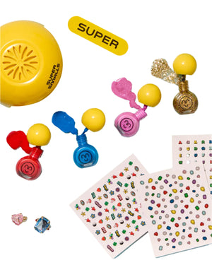The Self Care Nail Kit by Super Smalls features colorful nail polishes with yellow caps, peel-off polish, nail stickers, two fun rings, and a yellow "SUPER" dome—perfect for creating your own at-home nail salon.