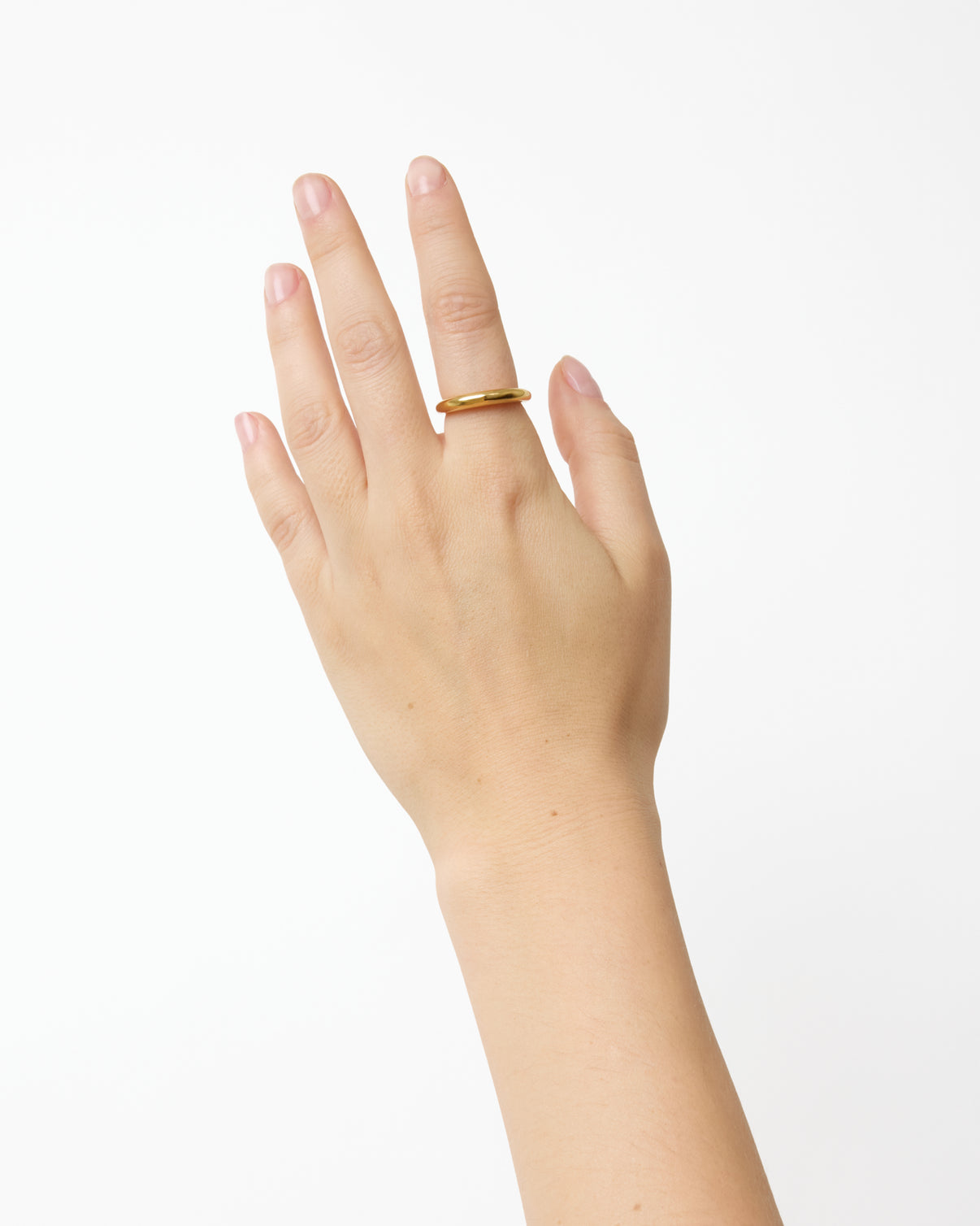 A left hand with neatly trimmed nails wears the Nanna Ring by Lie Studio—a classic curved band made of 18 carat gold-plated sterling silver—on the middle finger, set against a plain white background.