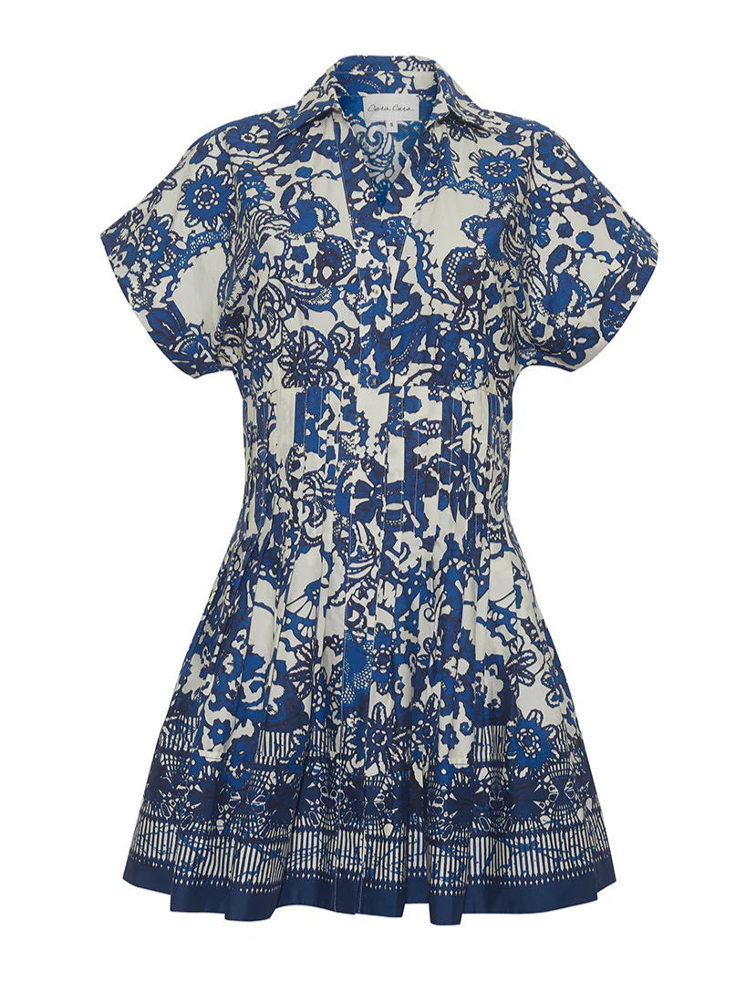 The Cara Cara Nash Mini Dress is a charming mini shirtdress with short sleeves, a blue and white floral pattern, pintucks, a pleated skirt, and functional pockets for convenience.