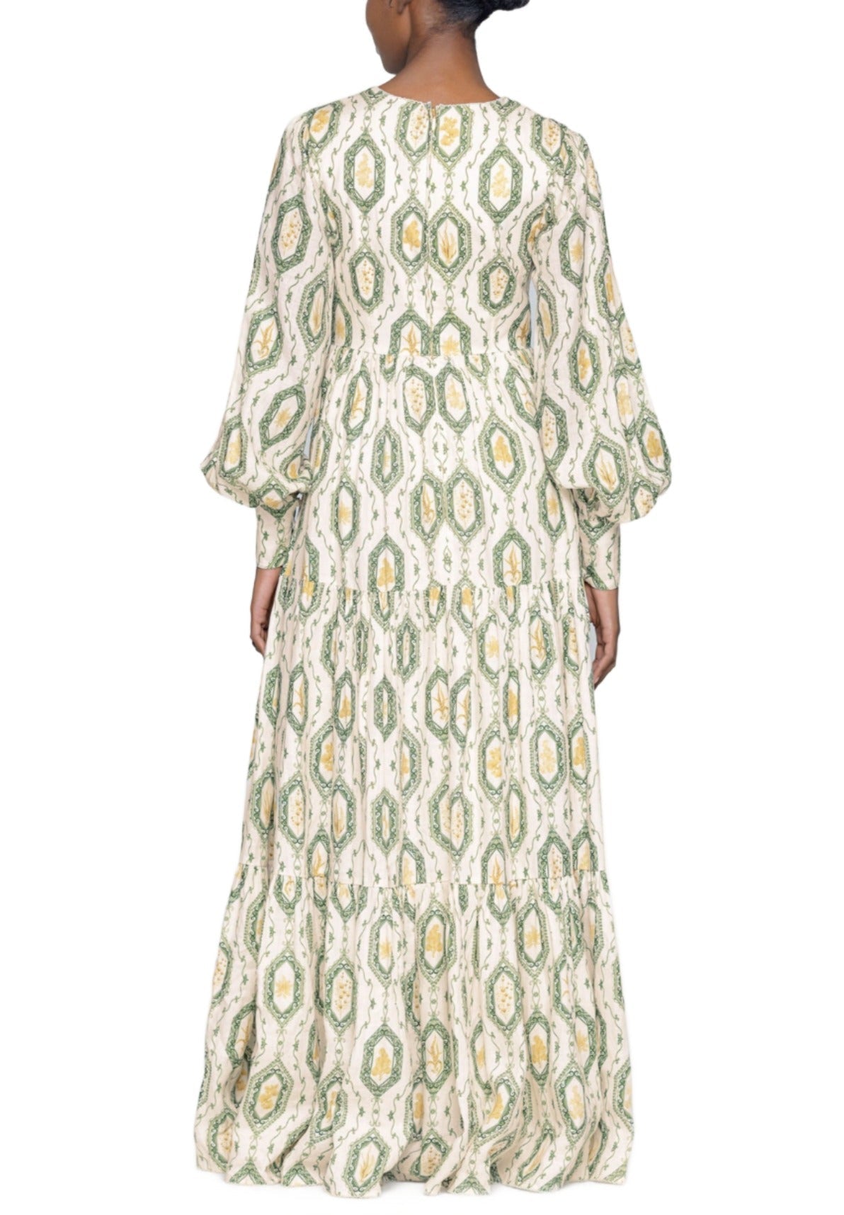 Rear view of a woman wearing an Agua by Aguabendita Nuez Maxi Dress with green and white paisley patterns, featuring wide sleeves and a full-length design.