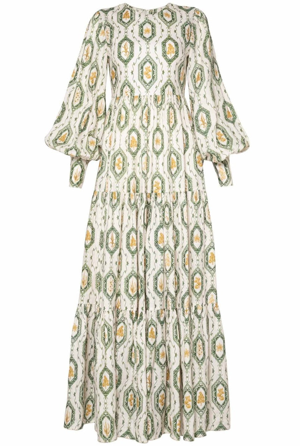 A long, flowing linen Agua by Aguabendita Nuez maxi dress featuring an ornate green and yellow floral pattern on an off-white background, with three-quarter sleeves and gathered tiers.