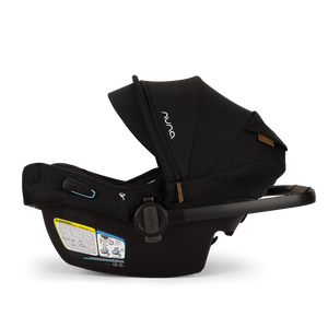 The Nuna Pipa Aire RX Carseat, a black infant car seat with canopy, features machine washable fabrics and safety instructions on the side. This lightweight and FAA certified car seat is ideal for convenient travel.