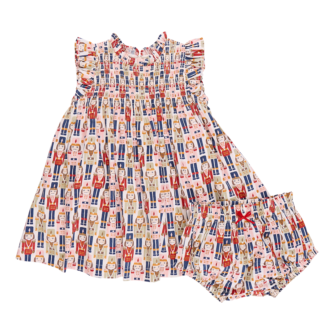 A vibrant Stevie Dress and matching bloomers by Pink Chicken, adorned with a Nutcracker-themed print featuring various Nutcracker characters in a repeated pattern.