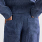Model wears the TWP Dylan Hemp Denim Pant, shown from the waist down with hands in the back pockets of these blue textured high-rise trousers.