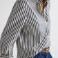 Wearing the TWP Next Morning Clear Sequin Stripe Shirt, an oversized Italian cotton button-down with vertical black-and-white stripes, tucked into high-waisted blue jeans and belted, upper body shown with face partially out of frame.