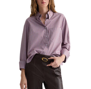 A person wears the TWP J.D. Framed Micro Striped Shirt with long sleeves, styled boxy, tucked into high-waisted dark pants and finished with a belt featuring a gold buckle.