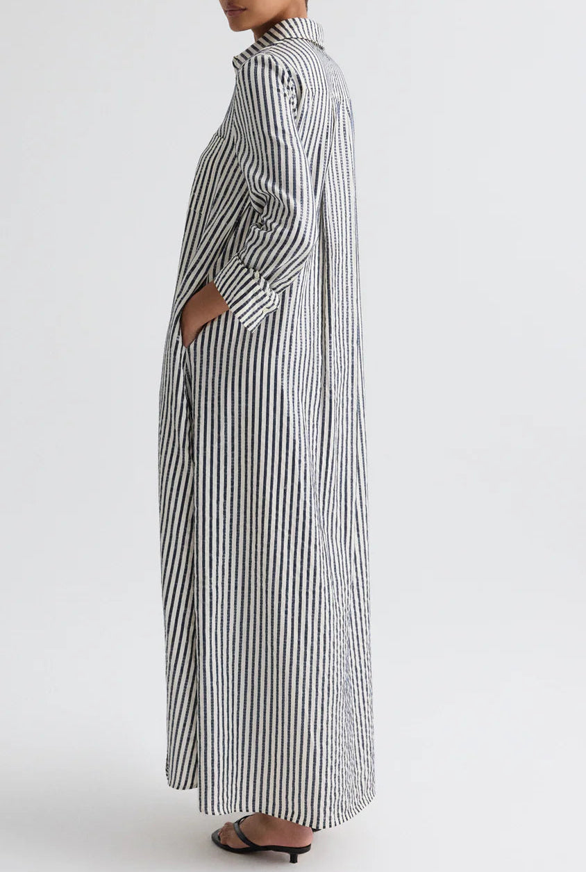 Person wearing the TWP Jenny's Clear Sequin Stripe Gown, featuring long sleeves and vertical black-and-white stripes, standing in profile against a plain background.