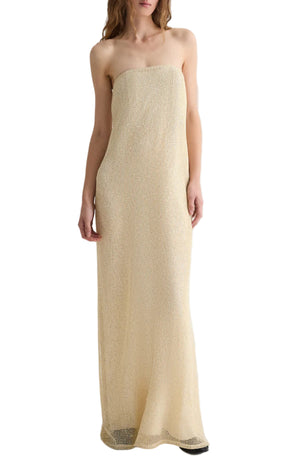A woman showcases effortless elegance in the Carolyns Sequin Netting Gown by TWP, a floor-length, strapless cream dress set against a white background.