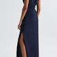 A person models the TWP Gathered Thoughts Dress in navy blue, featuring an open back, side slit, and keyhole detail, paired with black sandals against a plain light background.