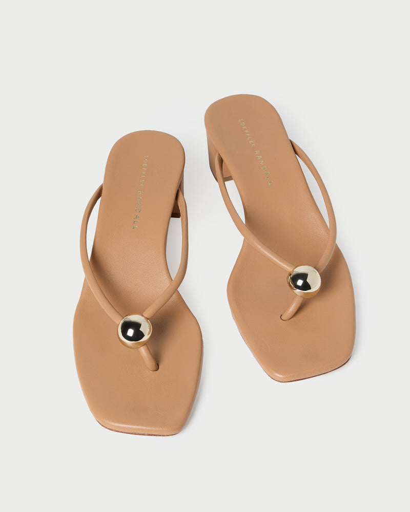 The Odessa Heeled Mule by Loeffler Randall features tan nappa leather, a square toe, thin straps, and a gold ball accent on each strap. Shown on a white background.