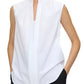 Wearing the Olympia Sleeveless Top by Callas Milano in white, paired with black pants and hands in pockets, exudes a modernist appeal.