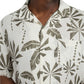 Someone is wearing the Onia Air Linen Vacation Shirt, a relaxed-fit white short-sleeve shirt with a green leaf pattern, made from breathable air linen fabric—perfect for vacation.
