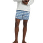 A person models the Onia Charles 5" Swim Trunk, wearing a long-sleeve white shirt. The blue patterned trunks are made from quick-dry fabric, set against a plain background.