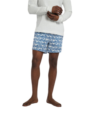 A person models the Onia Charles 5" Swim Trunk, wearing a long-sleeve white shirt. The blue patterned trunks are made from quick-dry fabric, set against a plain background.