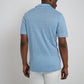 A man stands with his back to the camera, wearing the Onia Shaun Linen Polo in light blue and white shorts against a plain background.