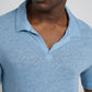 Someone wears the Onia Shaun Linen Polo in light blue, featuring a relaxed fit and Johnny collar, shown from shoulders to upper chest, facing slightly to the side.