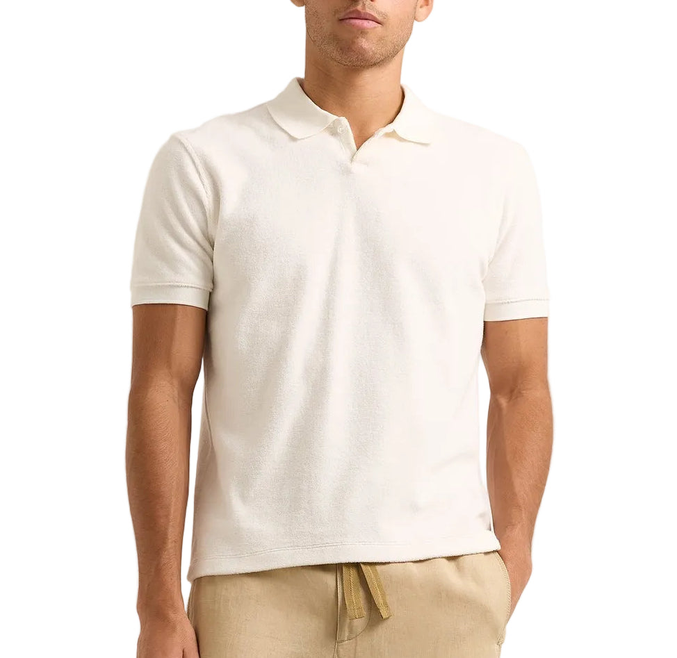 A man wearing the Orlebar Brown Bruno Towelling Polo in off-white and light beige pants stands against a plain background.