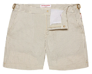 The Orlebar Brown Bulldog Classic Stripe Short features beige and white stripes, signature side-fasteners, a partially open front flap, and a visible waistband label—ideal for those wanting refined swimwear style.