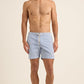 A shirtless man stands facing forward against a plain beige background, wearing Orlebar Brown's Bulldog Drawcord Seersucker Short—lightweight swim trunks with a rope-style drawcord and subtle stripes.