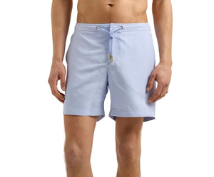 A man wears Orlebar Brown's Bulldog Drawcord Swim Short in light blue, featuring quick-drying fabric and a rope-style drawcord waistband, standing against a plain white background.