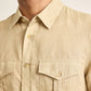 A close-up of a person wearing the Orlebar Brown Colburn Lino Shirt, a beige linen button-up featuring two chest pockets and a pointed collar.