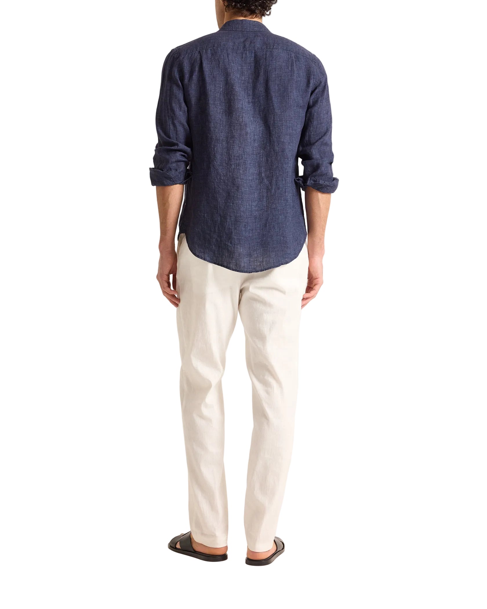 A person stands facing away, wearing the Orlebar Brown Colburn Lino Shirt in navy, paired with off-white pants and black sandals, against a plain white background.