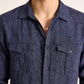 A person is wearing the Orlebar Brown Colburn Lino Shirt—a dark blue, tailored long-sleeve linen shirt with two chest pockets—shown in a photo from shoulders to mid-torso.
