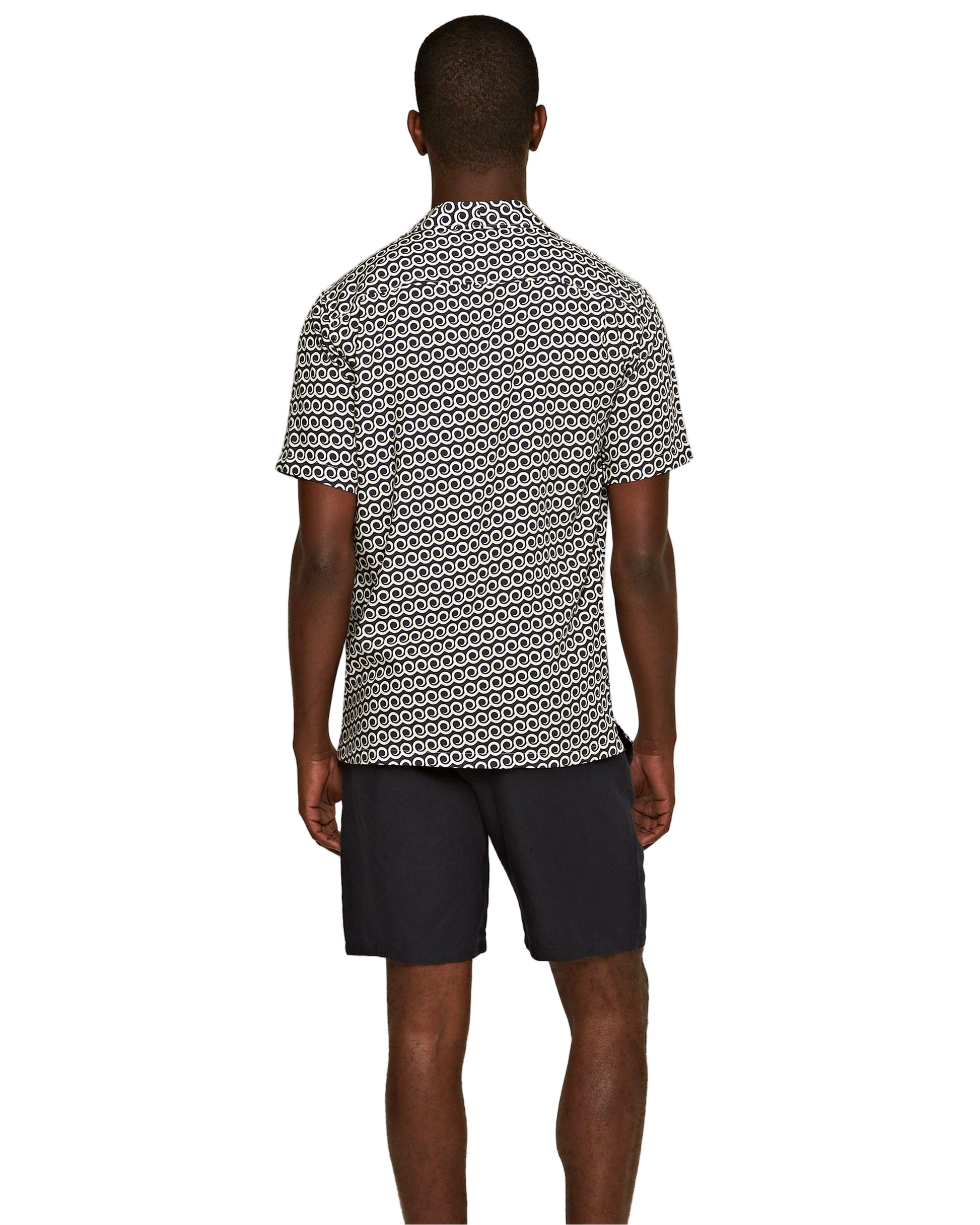 A man faces away against a plain white background, wearing a short-sleeve patterned shirt and Orlebar Brown’s Cornell Linen Short—dark Italian-woven linen shorts with an elasticated waistband.