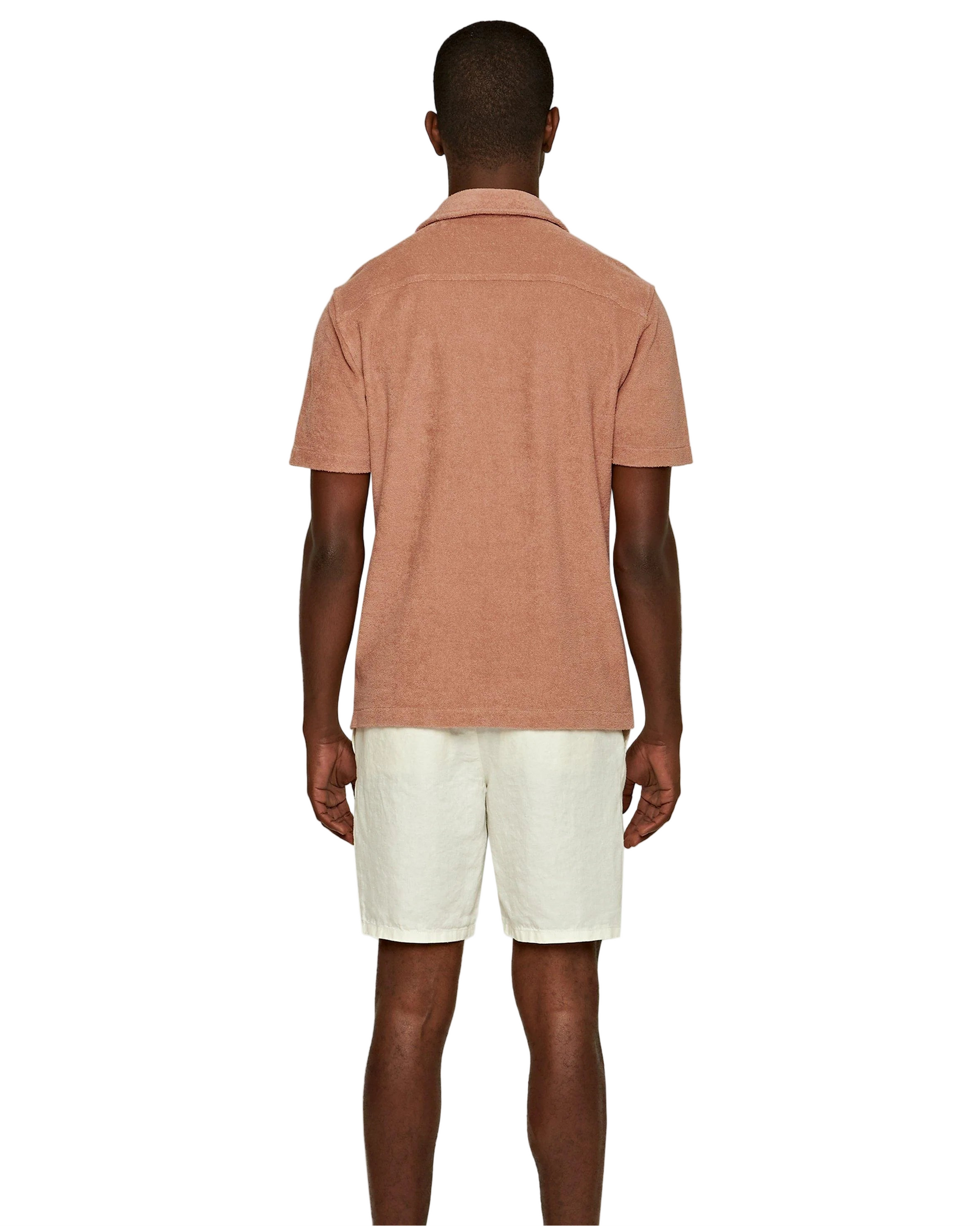 A man, facing away from the camera, wears a light brown short-sleeve shirt and Orlebar Brown Cornell Linen Shorts with an elasticated waistband, set against a plain white background.