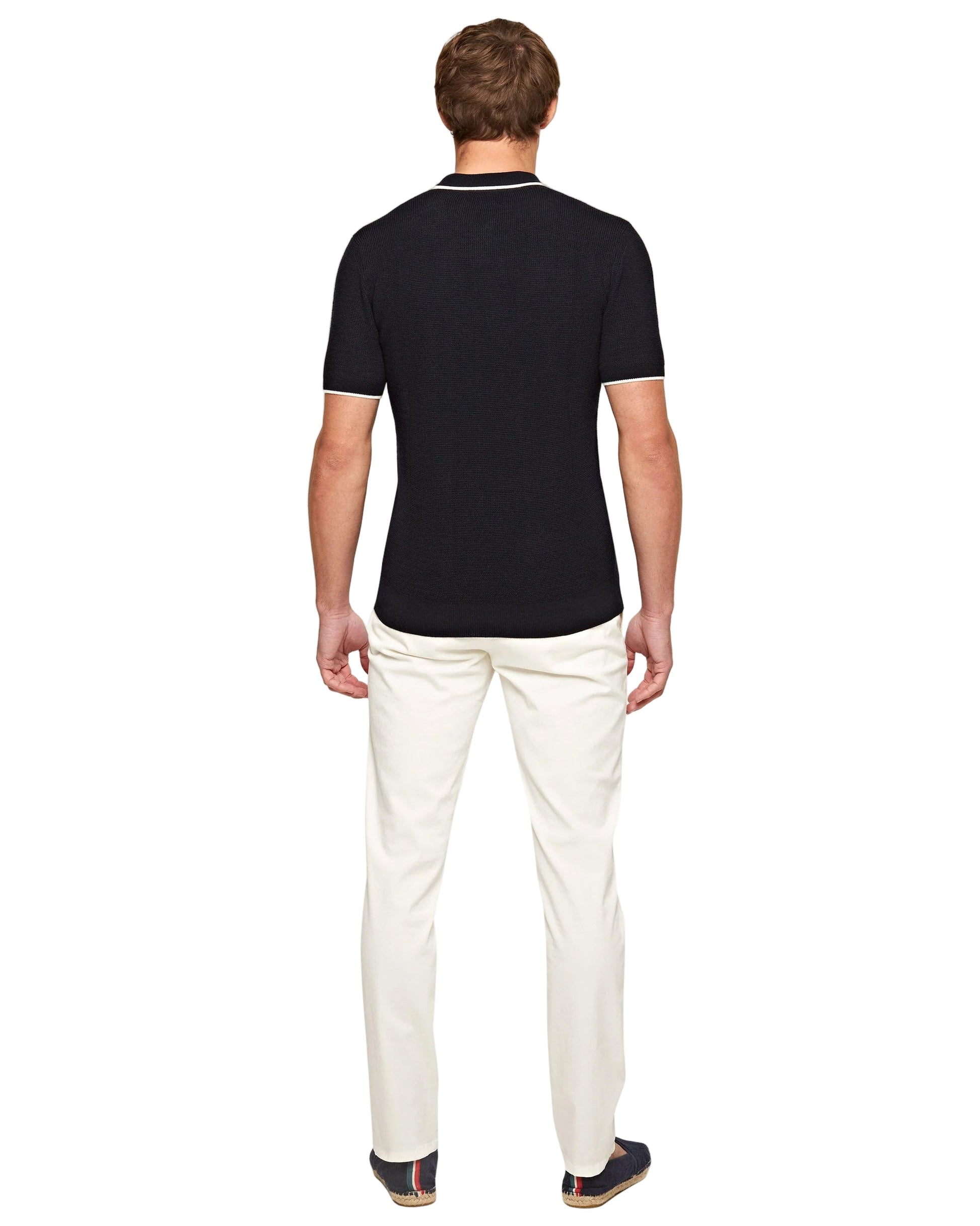 Man facing away on a white background, wearing a short-sleeve black polo shirt, Orlebar Brown Fallon Stretch-Cotton Pant, and dark shoes.