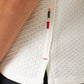 Close-up of the Orlebar Brown Maitan Open Weave Shirt with a Capri collar and side slit, featuring small multicolored stitched accents near the edge, paired with black pants.