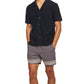 A man in shorts and a black Orlebar Brown Maitan Seersucker Woven Shirt.