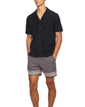 A man in shorts and a black Orlebar Brown Maitan Seersucker Woven Shirt.