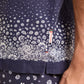 Close-up of a person's torso wearing the Orlebar Brown Maitan Plant Shirt with a Capri collar and small tag, paired with matching floral shorts.