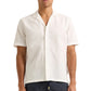 A man wearing the Orlebar Brown Maitan Seersucker Woven Shirt with a Capri collar and textured pattern stands against a plain background.