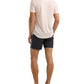 A man stands with his back to the camera, wearing a light pink Orlebar Brown Sebastian Linen Polo with a tailored fit, paired with dark shorts and black slide sandals against a white background.