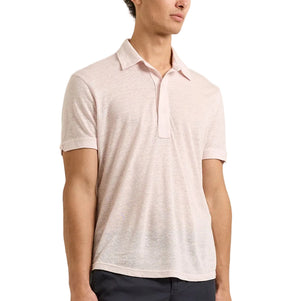 A man wearing a tailored fit light pink Sebastian Linen Polo by Orlebar Brown and dark pants, standing against a plain background.