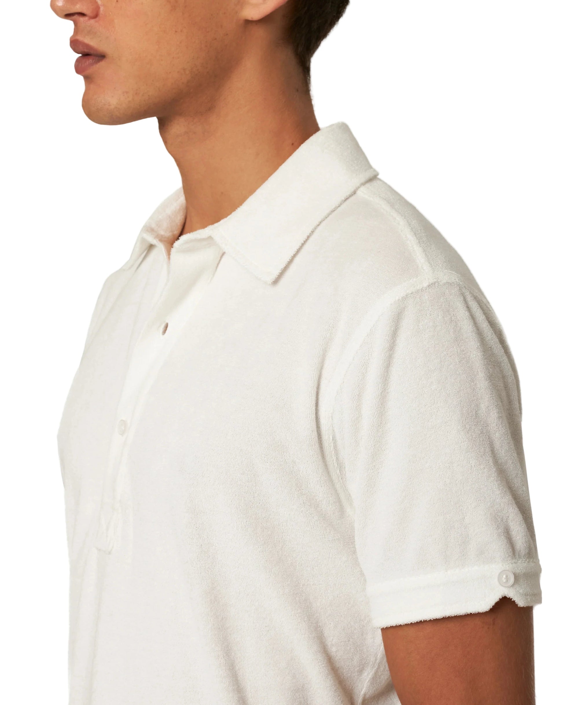 A person wearing a tailored fit, white Terry Polo by Orlebar Brown, shown from the side with only their head and upper torso visible.