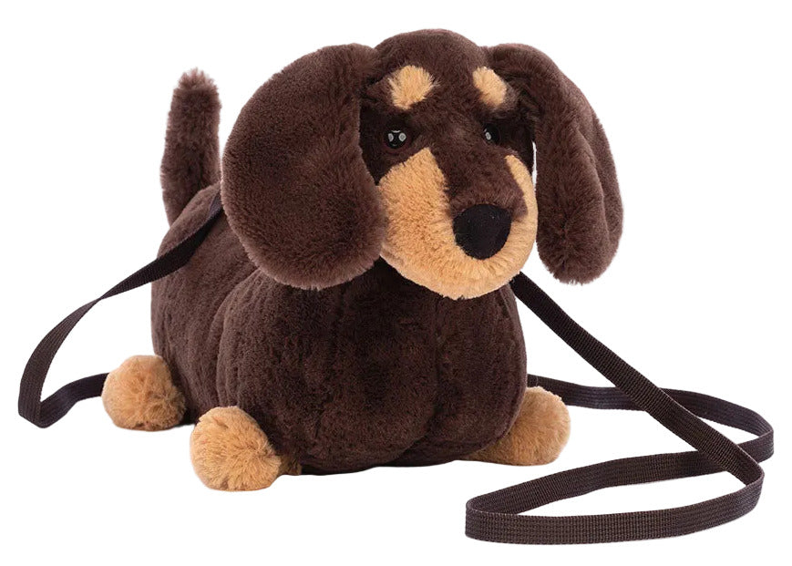 The Jellycat Otto Sausage Dog Shoulder Bag, shaped like a brown and tan dachshund with floppy ears and a leash strap, is an adorable city stroll accessory.