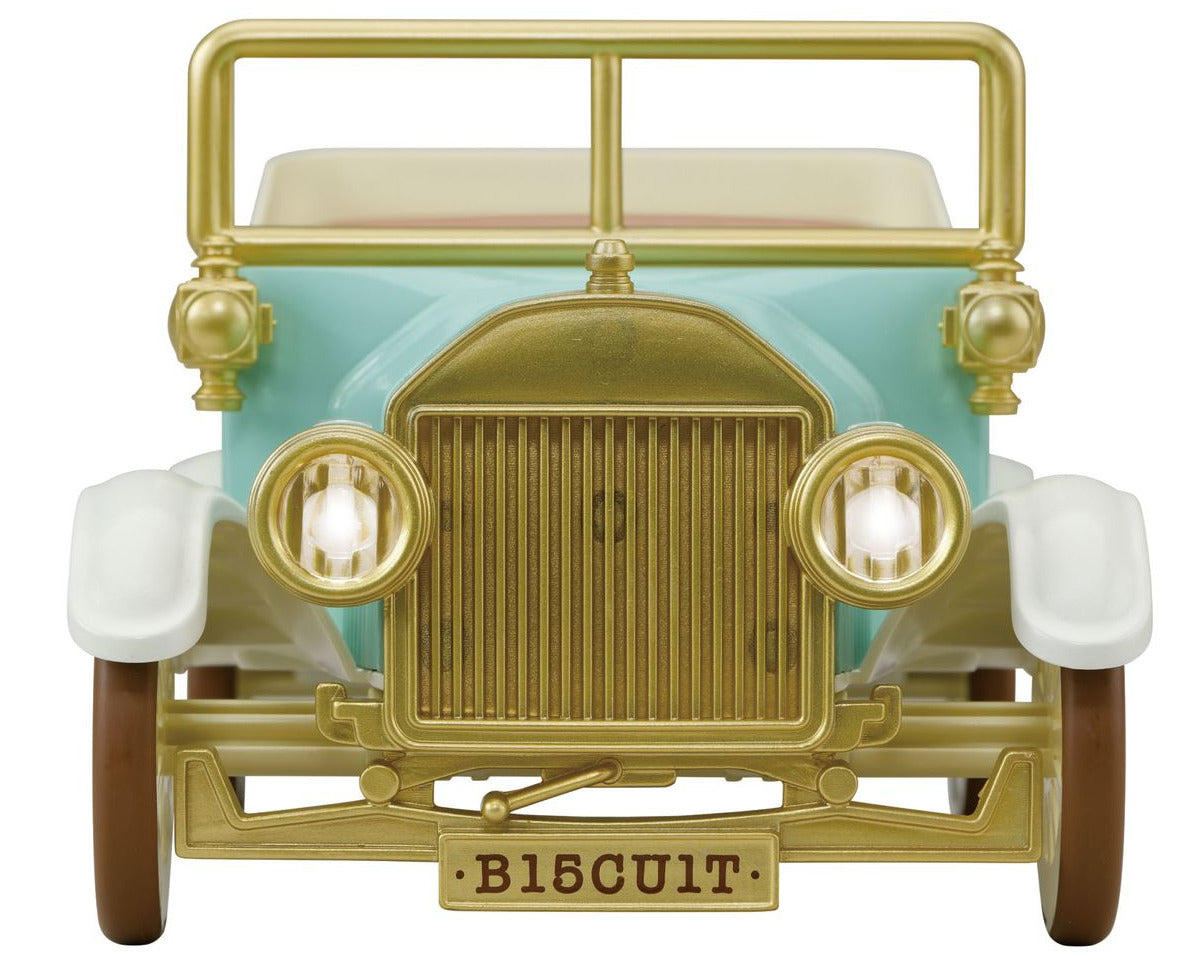 Front view of the Calico Critters Classic Family Car, showcasing a gold grille, mint green body, white fenders, brown wheels, and a license plate that reads “B15CU1T.” This detailed design features toy car accessories like a 10-figure seat for extra play value.