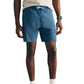 A person wearing a light grey t-shirt, white socks, grey sneakers, a black smartwatch, and Faherty Shorelite Swim Trunk—a blue technical swim trunk with quick-drying fabric and a comfortable compression liner—stands on a white background.