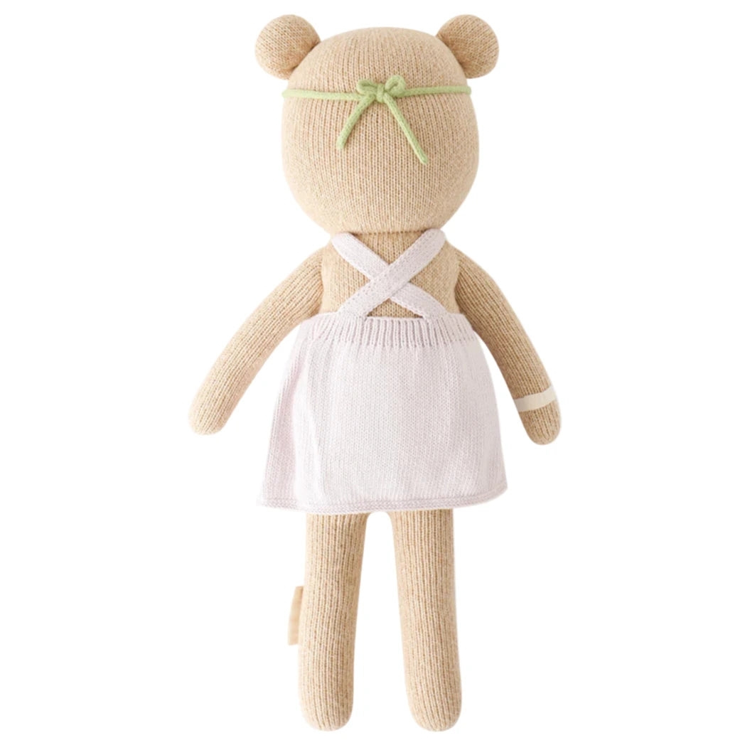 Charlotte the Dog - Little 13" by Cuddle + Kind, wearing a white apron-style dress and green headband, shown from the back—perfect for a garden tea party or to bring Bloom to any room.