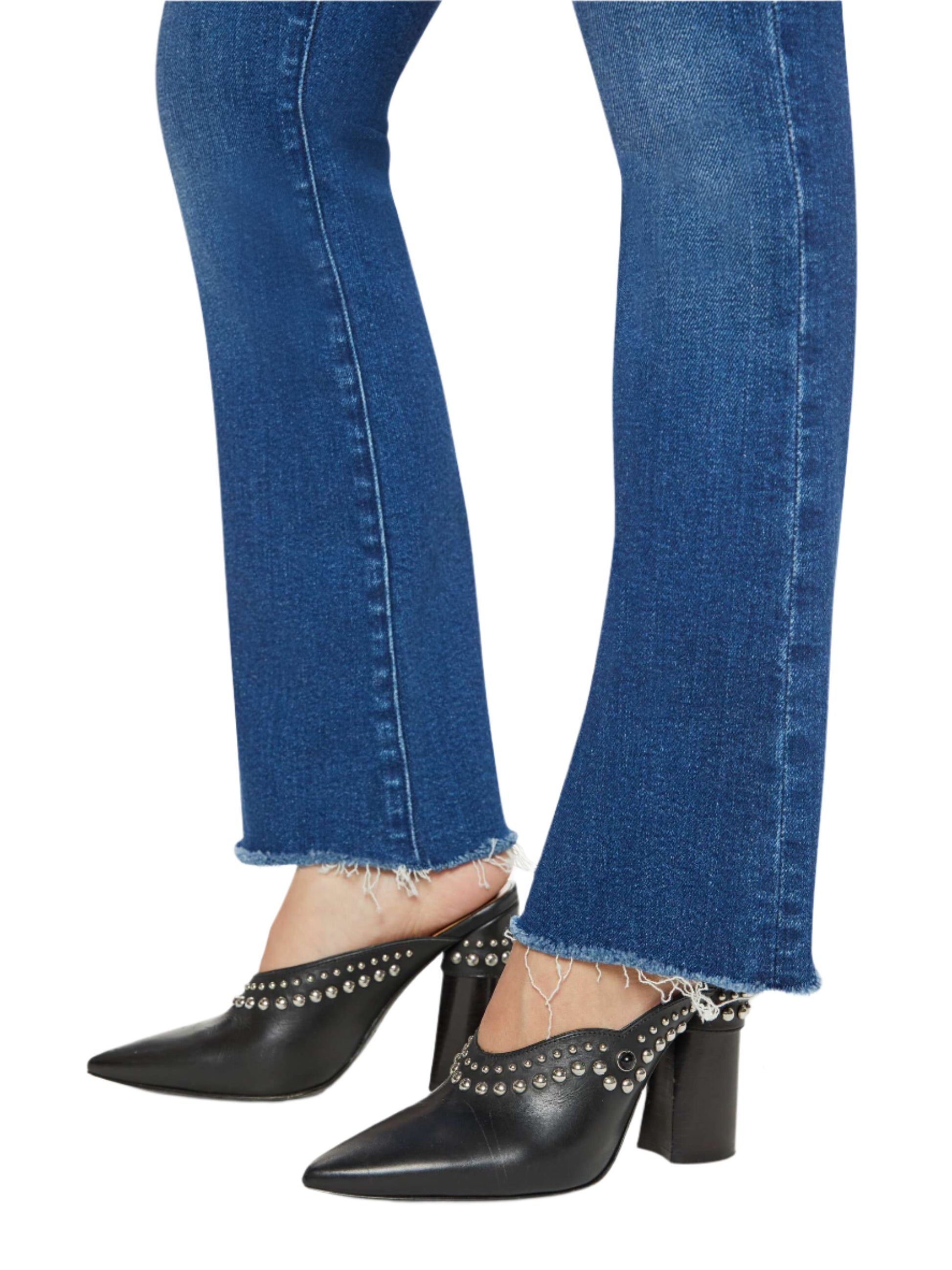 A person is wearing the Mother Denim Petites Lil Hustler Flood Fray jeans paired with black heeled mules adorned with metal studs.